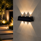 Three-lens solar wall light installed on a wall with warm up-and-down beams
